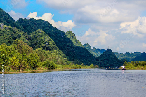 Tiny Boats Sail on the River Lined with Limestone Mountains Leading to the Perfume Pagoda in Vietnam © E. M. Winterbourne