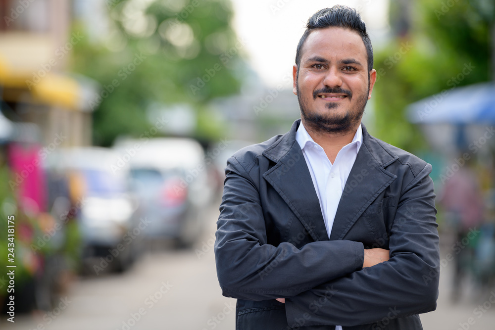 Happy bearded Indian businessman smiling with arms crossed outdoors Happy bearded Indian businessman smiling with arms crossed outdoors