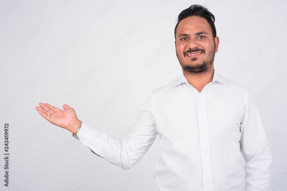 Studio shot of happy bearded Indian businessman showing something Studio shot of happy bearded Indian businessman showing something