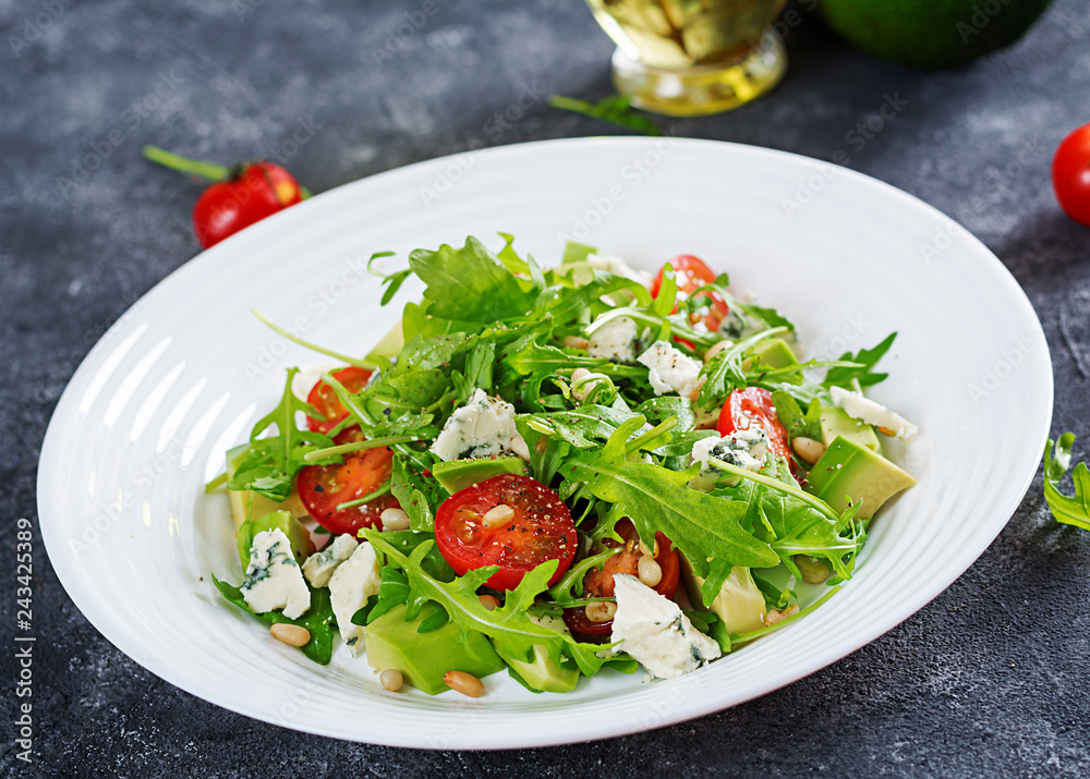 Dietary salad with tomatoes, blue cheese, avocado, arugula and pine nuts.