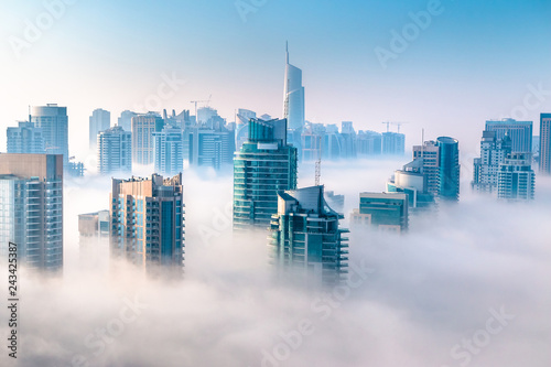 Aerial view of skyscrapers in the clouds. Morning winter fog over Dubai Marina. City above the clouds