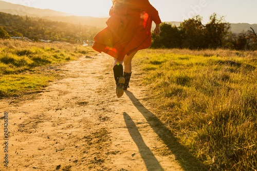Konstfotografi Tan mixed race woman wearing red dress runs away from viewer into sunset