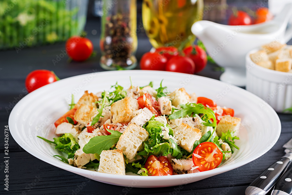 Healthy grilled chicken Caesar salad with tomatoes, cheese and croutons. North American cuisine.