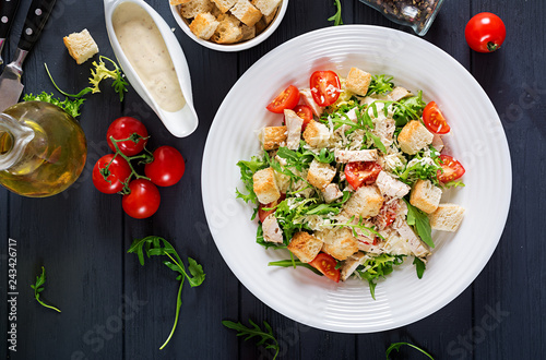 Healthy grilled chicken Caesar salad with tomatoes, cheese and croutons. North American cuisine. Top view