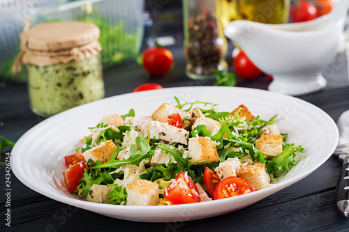 Healthy grilled chicken Caesar salad with tomatoes, cheese and croutons. North American cuisine.