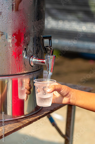 Hand boy holding the glass with water from the water cooler.
