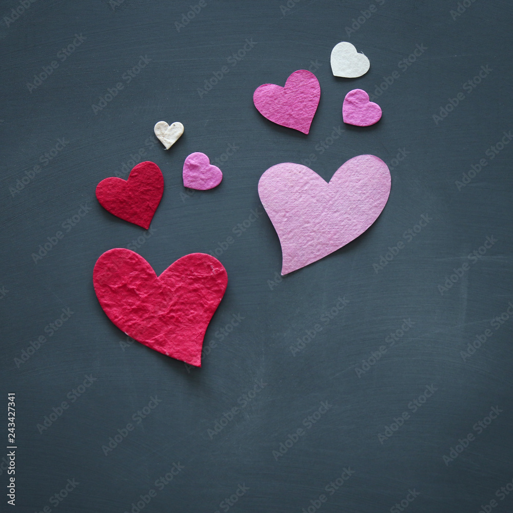 Fototapeta premium Valentine's day concept. pink and red paper hearts over blackboard.