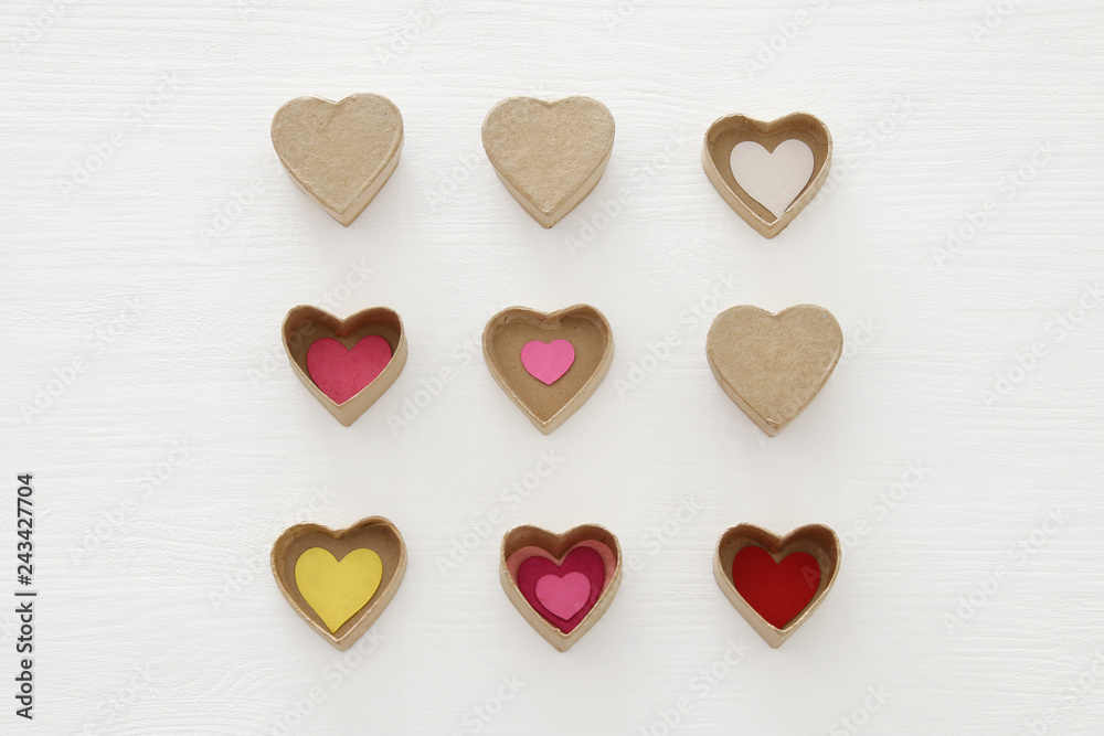 Valentine's day concept. hearts as paper gift boxes over wooden white background.