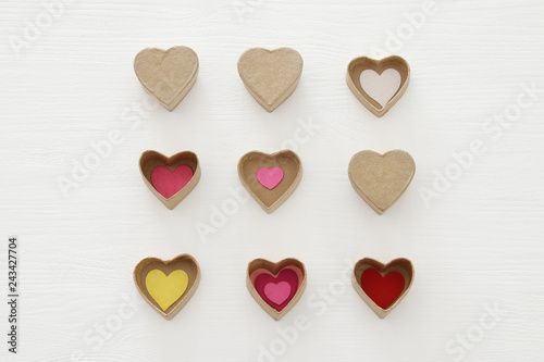 Valentine's day concept. hearts as paper gift boxes over wooden white background.