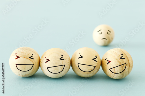 concept of bullying , discrimination. group of laughing emoticon faces and one alone look sad and depressed.