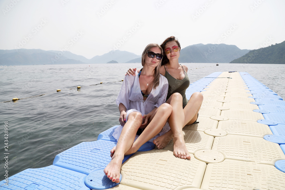 Two beautiful girls near the sea and mountains background