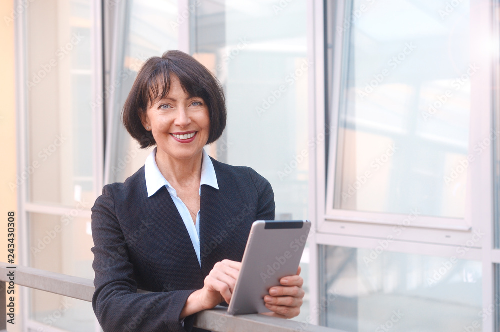 Mature businesswoman uses wireless tablet on urban street Mature businesswoman uses wireless tablet on urban street