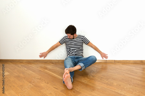 A young man is sitting on the floor in a new apartment.