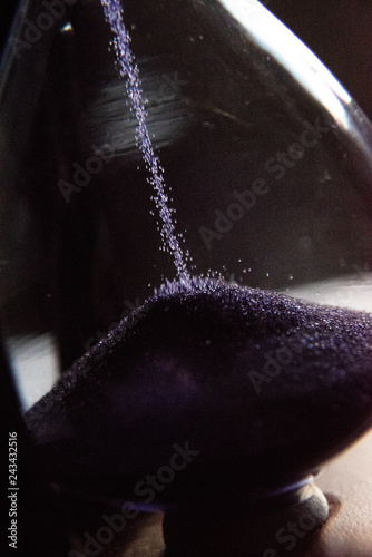 Closed up of sandglass or hourglass with violet, purple sand
