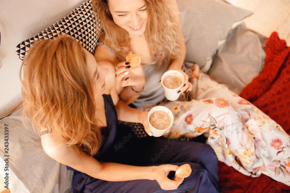 Two young girls in pajamas drink cocoa, laugh. Concept of Breakfast bed, lifestyle. Top view