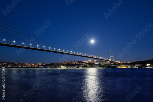Bosphorus Bridge illuminated by lights and moon at night