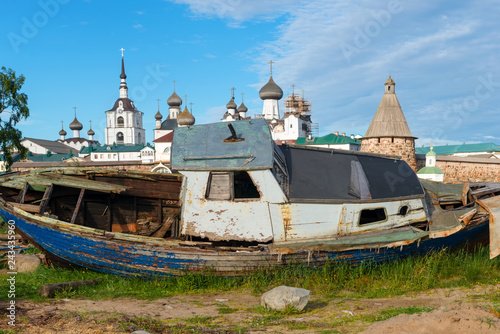 Old fishing boat on the shore against the background of the Transfiguration of the Solovetsky Monastery. Solovki, Russia