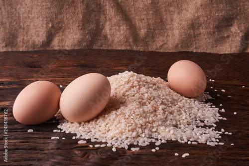 Bunch of rice and uncooced eggs on wooden table. Concept health food