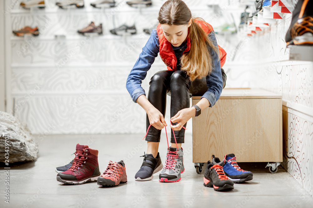 Φωτογραφία Woman trying shoes for mountain hiking sitting in the fitting room of the modern