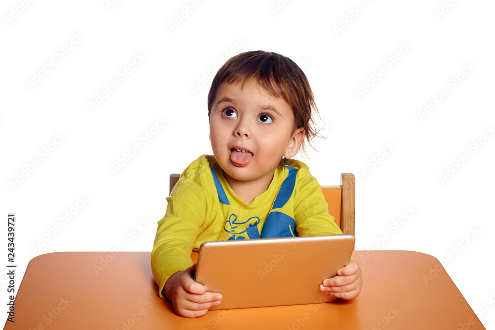 Adorable little child using digital tablet at desk, isolated on white background, shot in studio