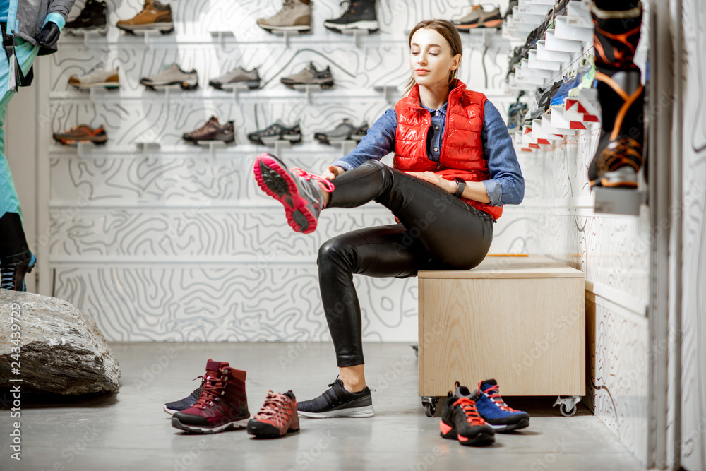 Φωτογραφία Woman trying shoes for mountain hiking sitting in the fitting room of the modern
