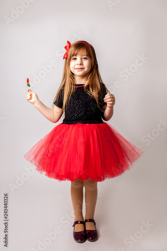 stylish little girl holding lollipop and to smiling, isolated on white