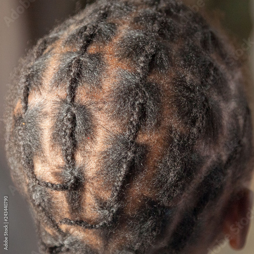 Small plaits looking like canerows on a young African girl from behind - black hair, brown skin, square format photo