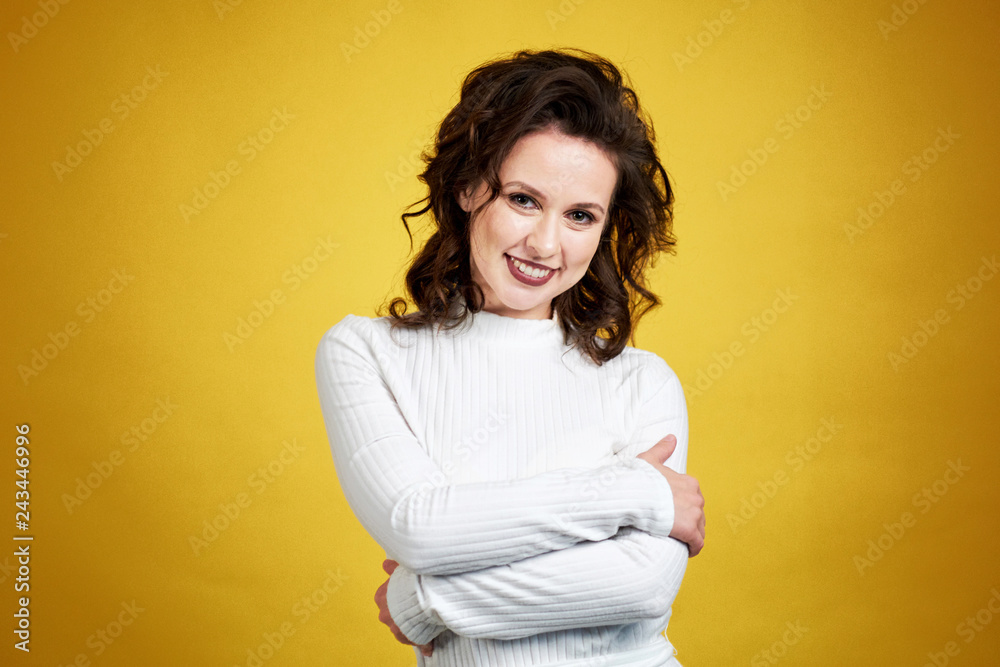Closeup portrait confident smiling woman holding hugging herself isolated blue wall background. Positive human emotion, facial expression, feeling, reaction, situation, attitude.