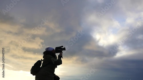 woman with video camera panoramic silhouette with scloudy sky background photo