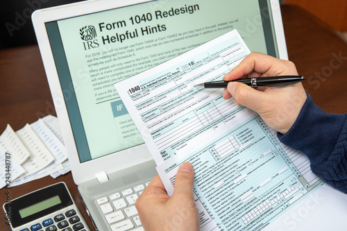 1040 Redesign Helpful Hints on a Laptop Monitor, Man's hand reviewing form 1040. photo