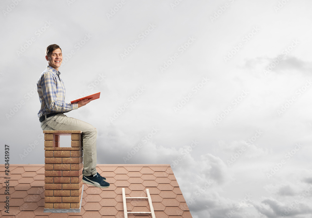 Handsome man on brick roof against cloud scape reading book Handsome man on brick roof against cloud scape reading book