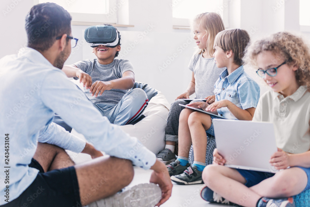 Obraz premium Happy boy uses VR glasses during technology lesson for kids at school
