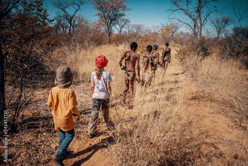 Kinder folgen einer Gruppe Buschmänner (Ju/'Hoansi-San) durch den Busch, Grashoek, Namibia photo