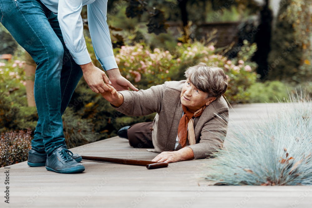 Ταπετσαρία Man helping female senior to get up from the ground