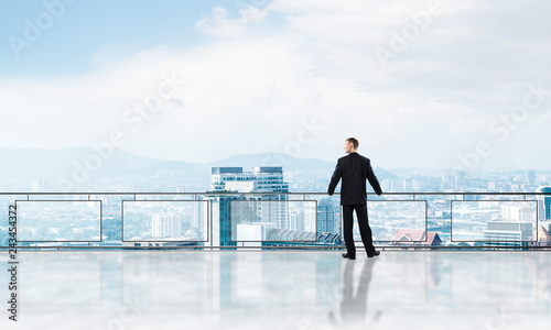 Sunrise above skyscrapers and businessman facing new day