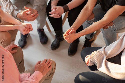 Close-up of hands of teenagers sitting in circle during a support meeting for people with impulse control and addiction disorders