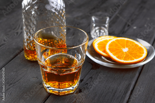 Whisky glass with orange fruit cut on dark wooden background