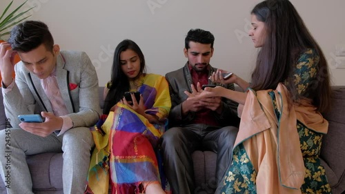 One friends tries to get attention of her friends seated on a couch and completely occupied with their smart phones on wifi surfing internet 