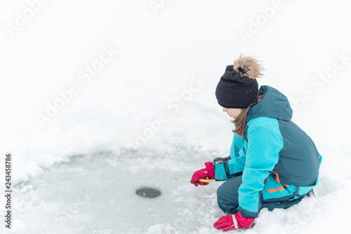 child fishing on ice in winter