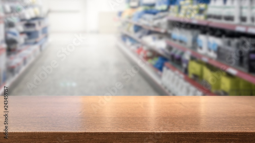 Wooden table top for product display montage. Blured shelves with groceries in store in the background. Hardware shop concept.