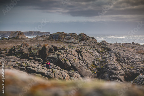 young woman sitting on rocks  of the island of Yeu photo