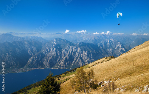 View on Alps and a paraglider over Garda lake from the mountain Monte Baldo, Lombardy, Italy.