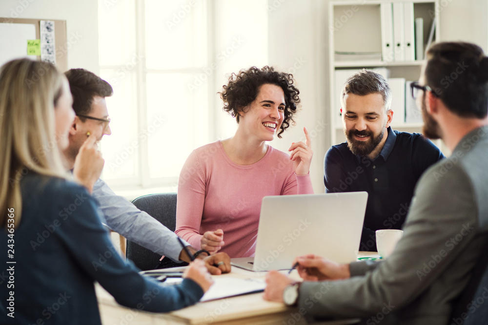 Group of young businesspeople sitting around table in a modern office, having meeting. Group of young businesspeople sitting around table in a modern office, having meeting.