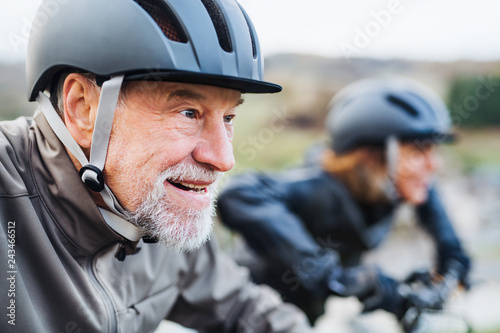 Active senior couple with electrobikes cycling outdoors on a road in nature. © Halfpoint