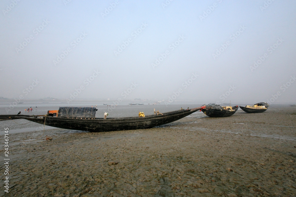 Boats of fishermen stranded in the mud at low tide on the river Malta near Canning Town, India 