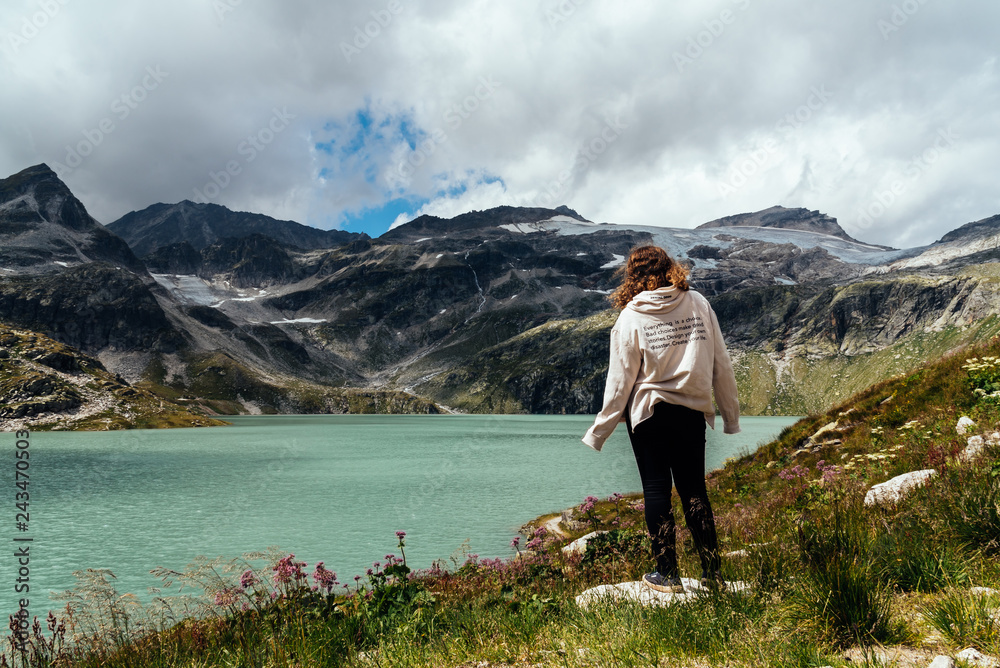 Young woman looking at mountain lake in the Alps