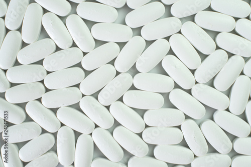 Detail of many white pills of medicines produced by the pharmaceutical and health chemistry industry, seen from above.