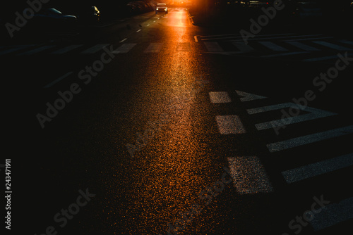 Urban background of a dark street at dusk with cars and traffic marks