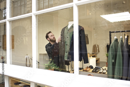 A proud shop owner dressing a mannequin