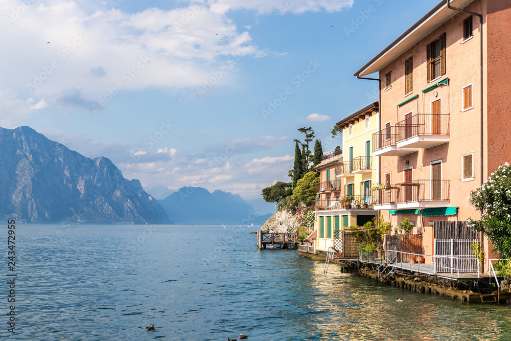 Idyllic italian lake landscape: Colorful houses, mountains and skye with clouds